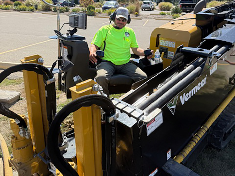 6 1 1 Boring and Excavating employee operating a directional boring machine near a parking lot